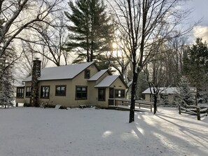 A two-story house with a snow-covered yard, a chimney, and a small porch. - Lakefront Cabin #8 The Musky House (Presque Isle)
