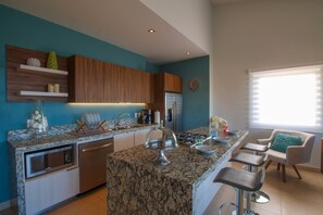 A modern kitchen with a central island, built-in appliances, and bar stools.