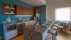 Une cuisine moderne dotée de plans de travail en granit, d’appareils électroménagers en acier inoxydable et d’armoires en bois.