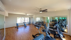 A spacious gym with treadmills, weight machines, and a mirror wall.