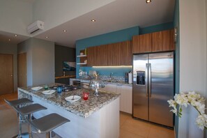Une cuisine moderne dotée d’un îlot central, d’appareils électroménagers en acier inoxydable et d’un mur d’accent bleu.
