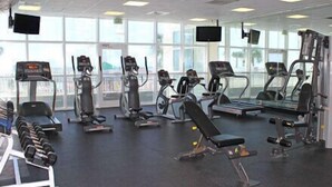 Uma academia com esteiras, elípticos e bancos de musculação.