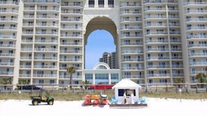 Um hotel grande com várias varandas e um arco central.