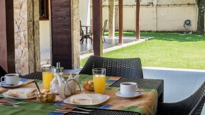 A breakfast setup with a table, chairs, and a view of a grassy area and a brick wall. - Hotel BY Armonia SCZ (Santa Cruz)