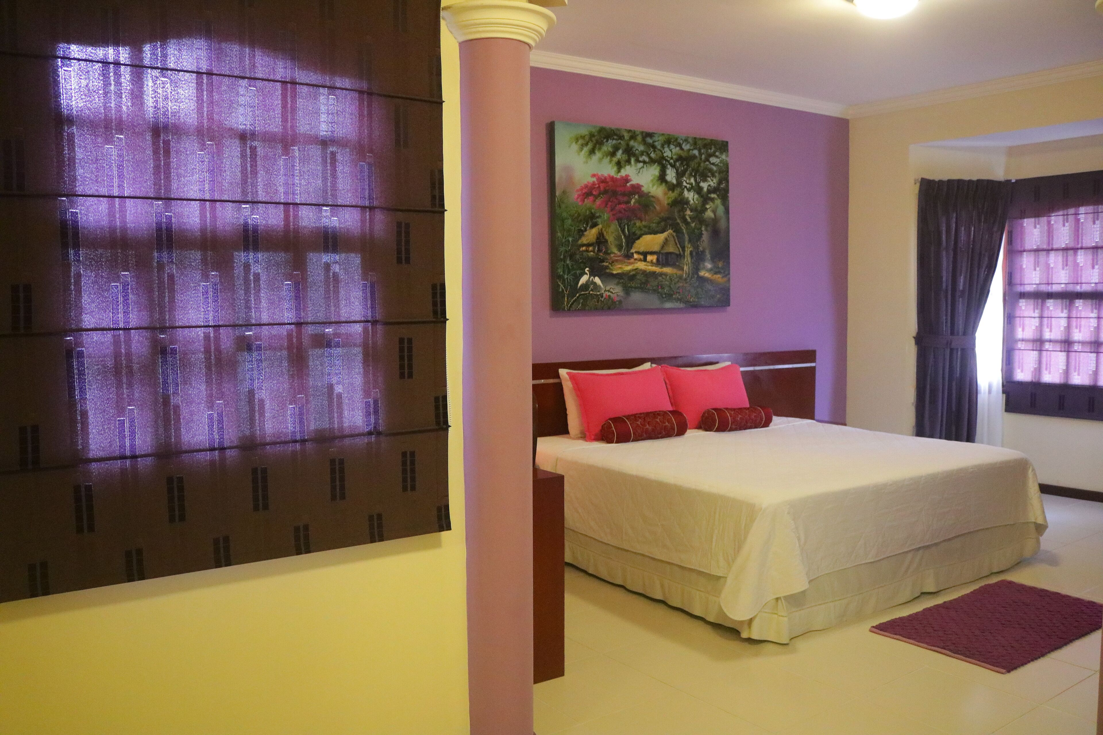 Une chambre d’hôtel avec un lit, un tableau au mur et une fenêtre avec des rideaux.