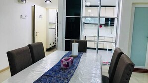 A dining area with a table, chairs, and a view through a glass door. - Ilman's Loft@Vista Alam HILLVIEW-PS4-500MBPS (Shah Alam)