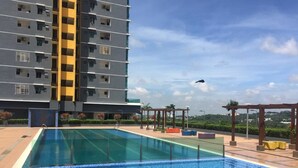 A swimming pool with a tiled deck, surrounded by a high-rise building with balconies. - Ilman's Loft@Vista Alam HILLVIEW-PS4-500MBPS (Shah Alam)