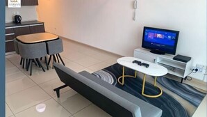 A modern living room with a sofa, a dining table, a TV, and a kitchen area. - Ilman's Loft@Vista Alam HILLVIEW-PS4-500MBPS (Shah Alam)