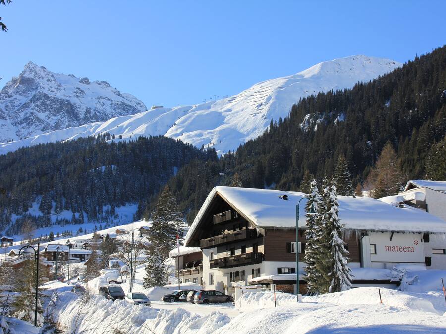 Une station de montagne enneigée avec un chalet doté de balcons et d’une enseigne indiquant « mateera ».