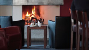 A cozy seating area with a fireplace, a table with a teapot and cups, and two chairs.