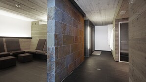 A modern lobby with a wooden ceiling, a large wall with a mix of stone and wood textures, and a seating area with dark-toned sofas and ottomans.