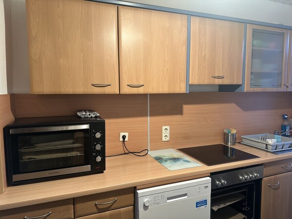 Una cocina con armarios de madera, horno empotrado, lavavajillas y fregadero.