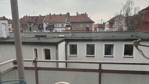 A balcony with a table and chairs, overlooking a residential area with houses and a clear sky. - Sultanias Homesharing (Nuremberg)