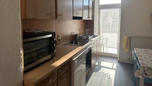 A kitchen with wooden cabinets, a built-in oven, a microwave, and a sink. - Sultanias Homesharing (Nuremberg)