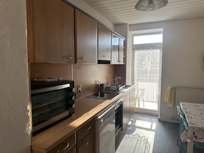 A kitchen with wooden cabinets, a built-in oven, a microwave, and a sink. - Sultanias Homesharing (Nuremberg)