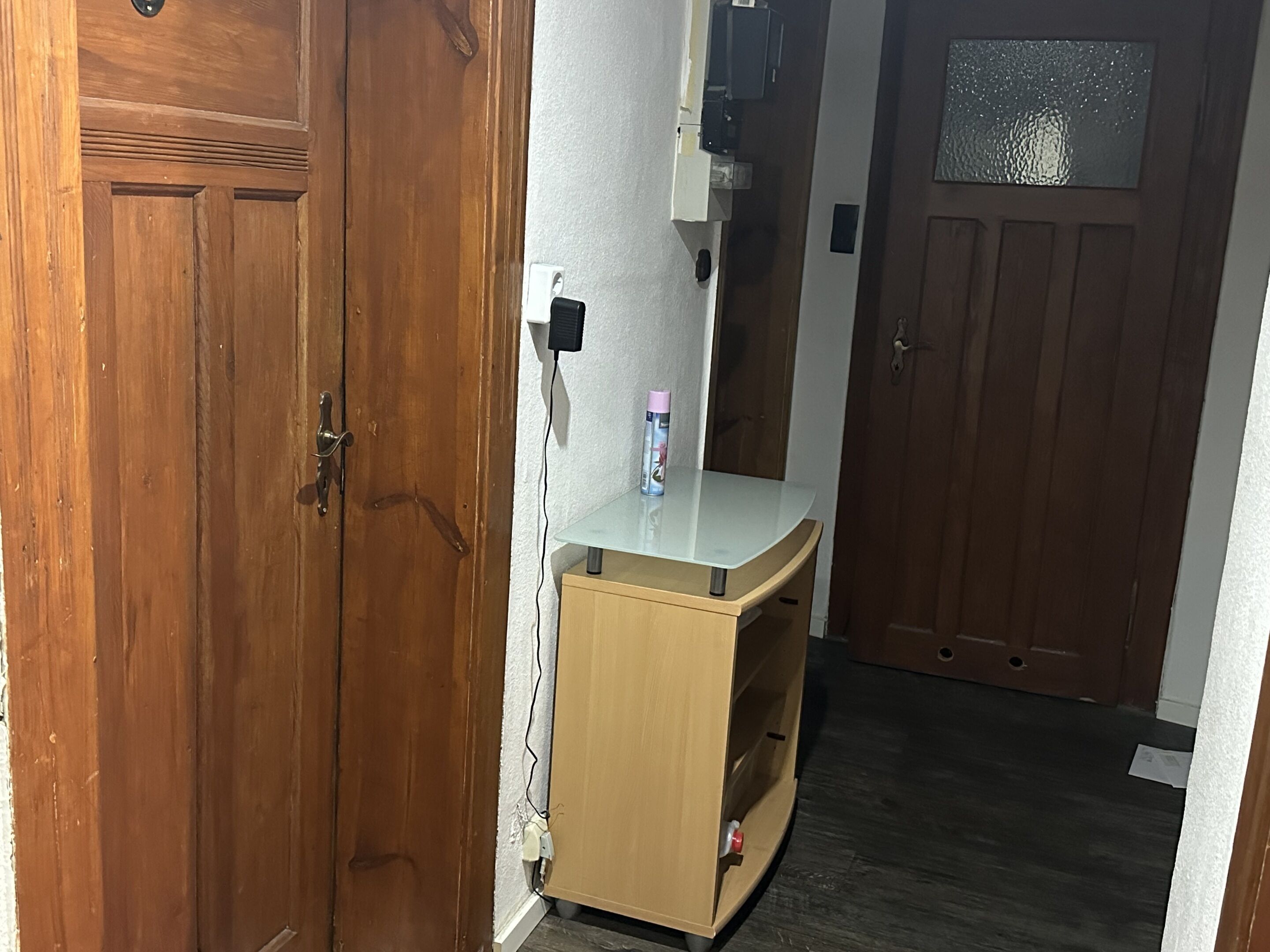 Eine Holztür mit Griff, ein kleiner Holzschrank mit weißer Arbeitsplatte und eine Glastür mit frostartigem Muster.