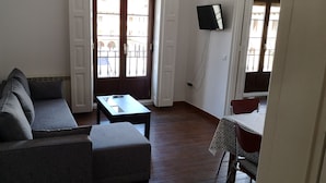 A living room with a sofa, a coffee table, and a dining table with chairs. - Apartamentos Plaza Mayor (León)