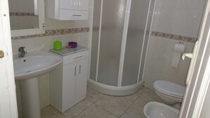 A bathroom with a sink, toilet, and shower. - Apartamentos Plaza Mayor (León)