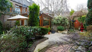 A garden with a wooden deck, potted plants, and a red lantern. - Castle Walk B&B (Stirling)