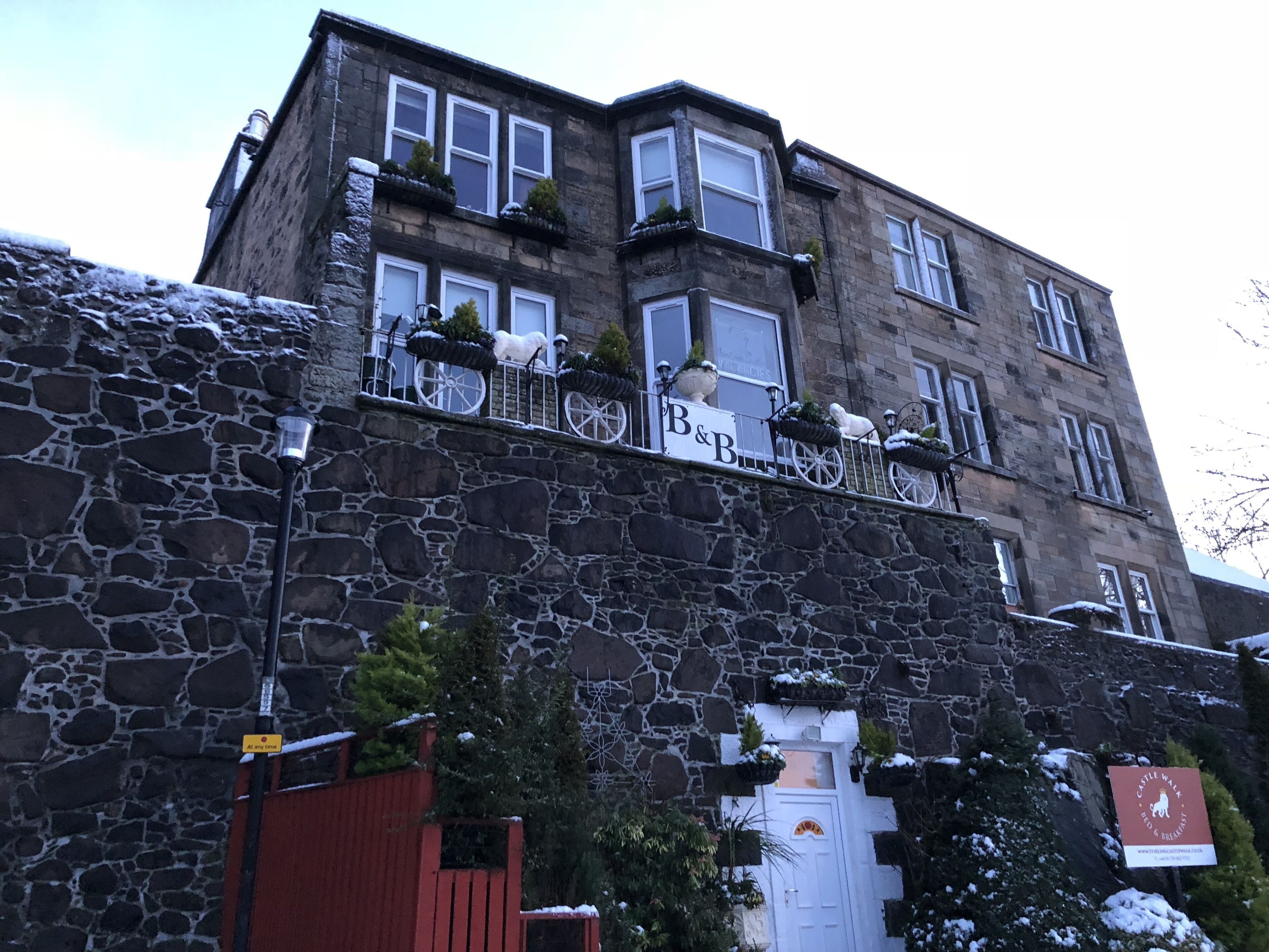 A stone building with multiple windows and a sign that reads "B&B".