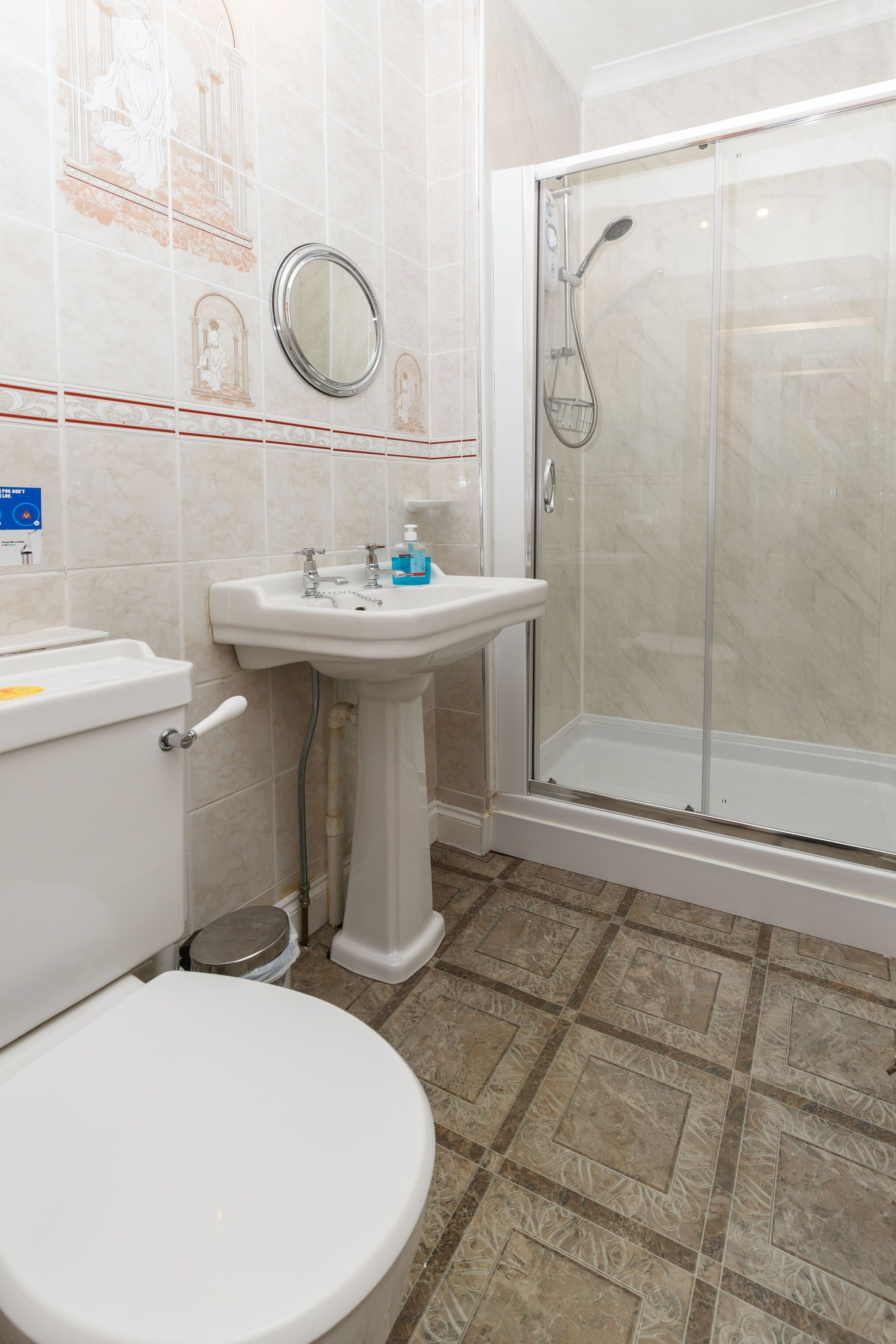 A bathroom with a toilet, sink, and glass-enclosed shower.