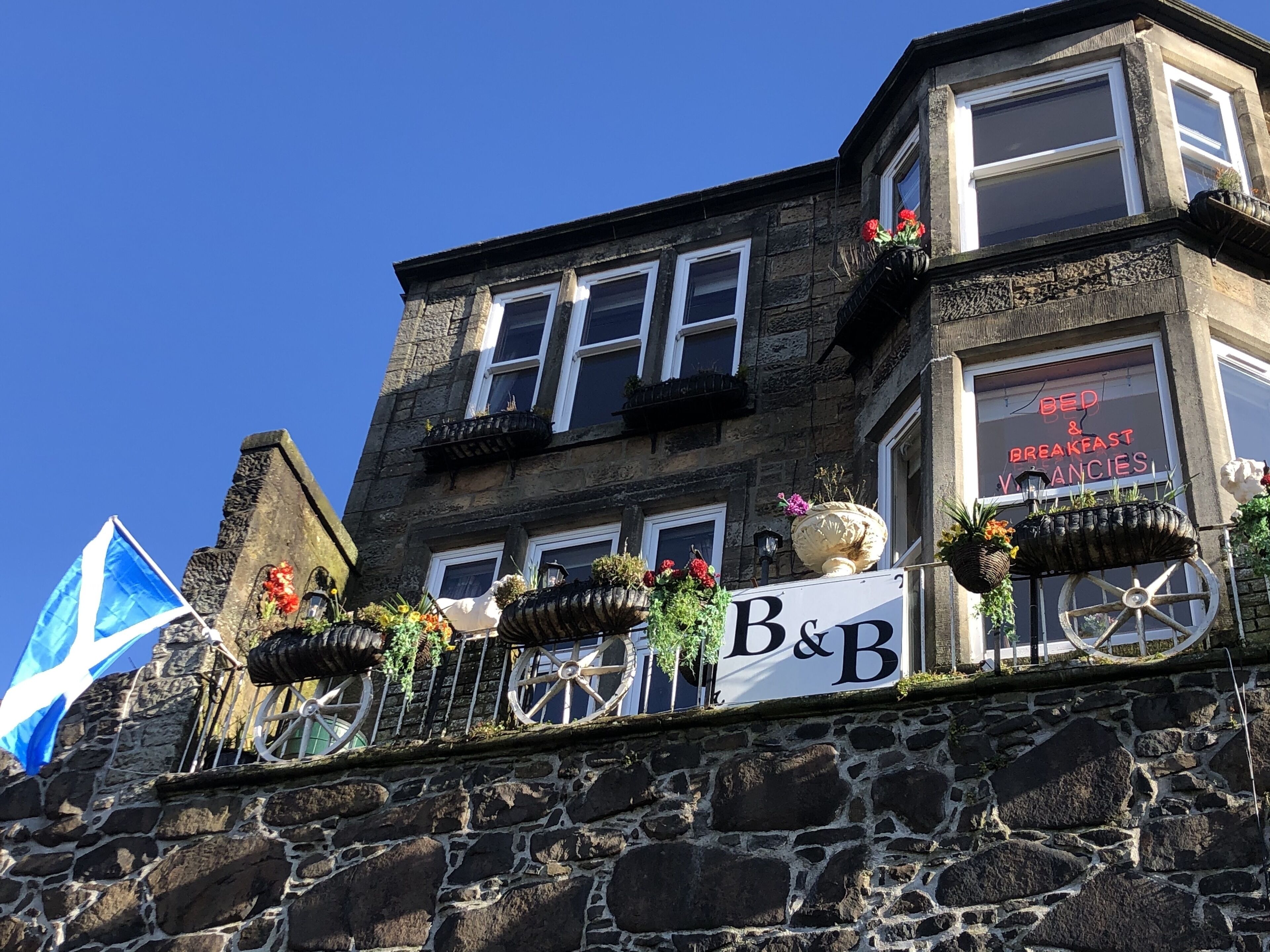 Un bâtiment en pierre avec une enseigne indiquant « Chambres d’hôtes et petit-déjeuner – places disponibles ».