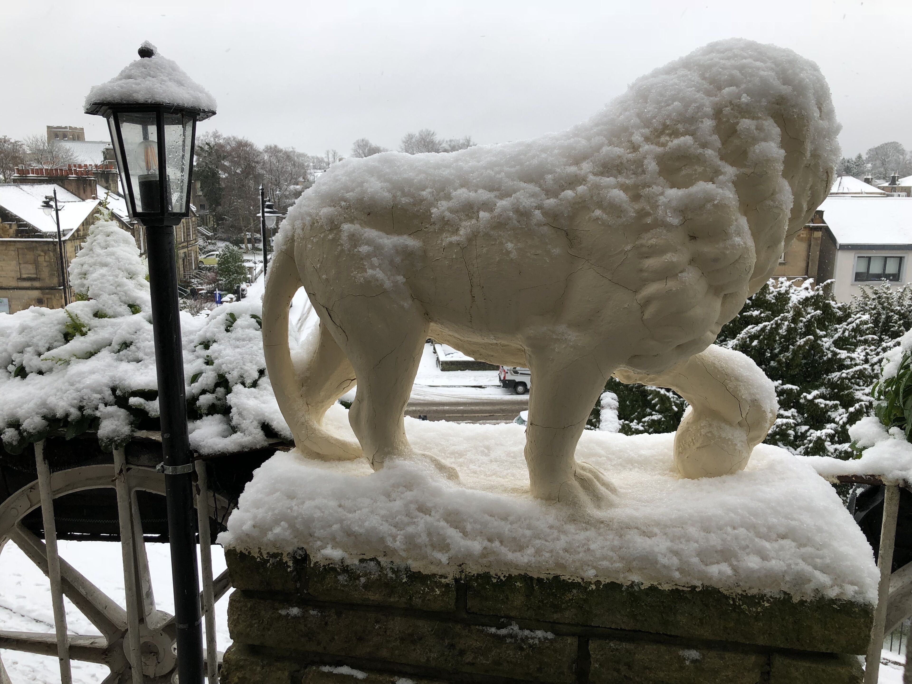 A snow-covered sculpture of a horse on a stone pedestal.