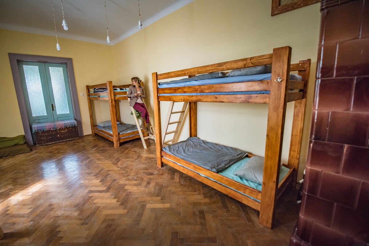 A room with three bunk beds, wooden flooring, a ladder, and a door with frosted glass panels.