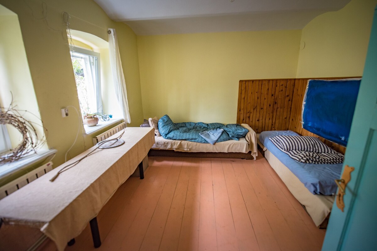A small, cozy room with two beds, a table, and a window.