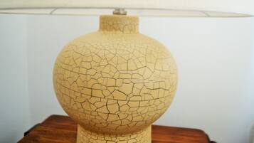 Une lampe dont l’abat-jour en verre est fissuré, posée sur une table en bois.