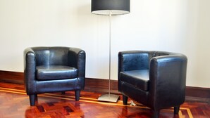 Deux fauteuils en cuir noir et un lampadaire dans une pièce dont le sol est recouvert de parquet.