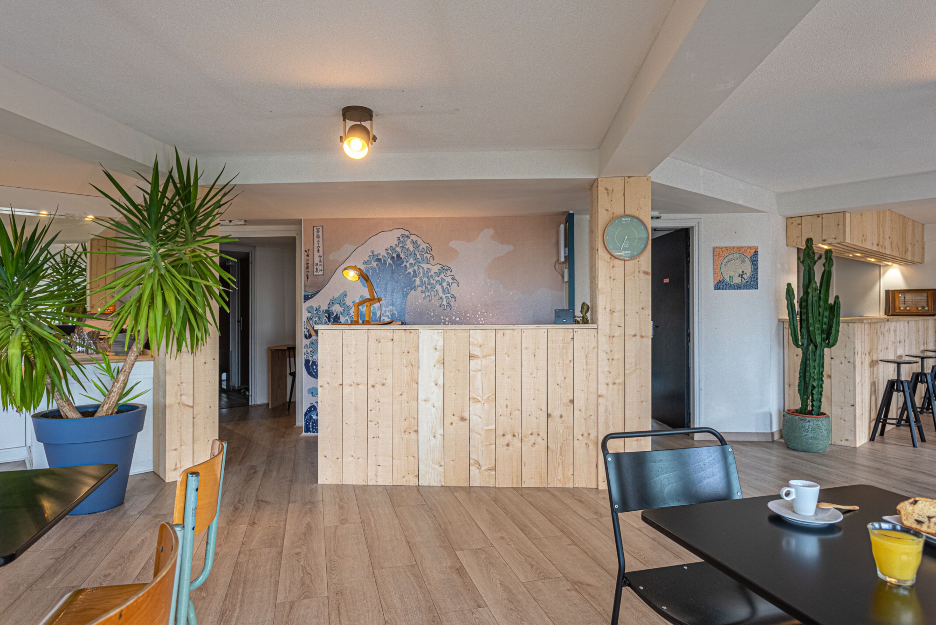A modern interior with wooden paneling, a reception desk, and a dining area with chairs and a table.