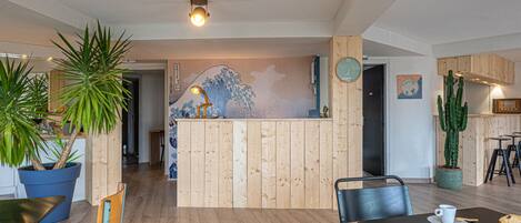 A modern interior with wooden paneling, a reception desk, and a dining area with chairs and a table.