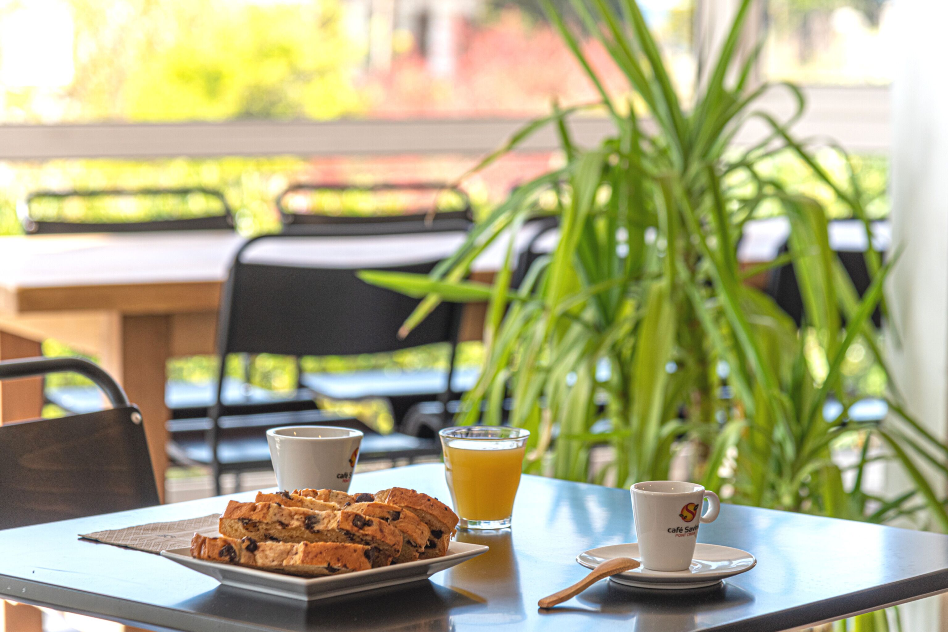 Una mesa con un plato de muffins, un vaso de zumo de naranja y una taza de café.
