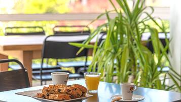 Una mesa con un plato de muffins, un vaso de zumo de naranja y una taza de café.