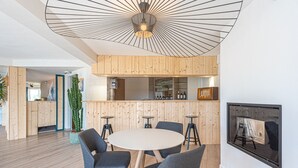 Un intérieur moderne avec une table ronde, des chaises grises, des murs recouverts de panneaux en bois et un luminaire au plafond.