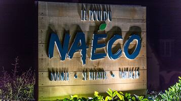 Un letrero de madera con las palabras "NAECO" y "DORMIR SE RELAXER PARTAGER", que indica un hotel o casa de huéspedes.