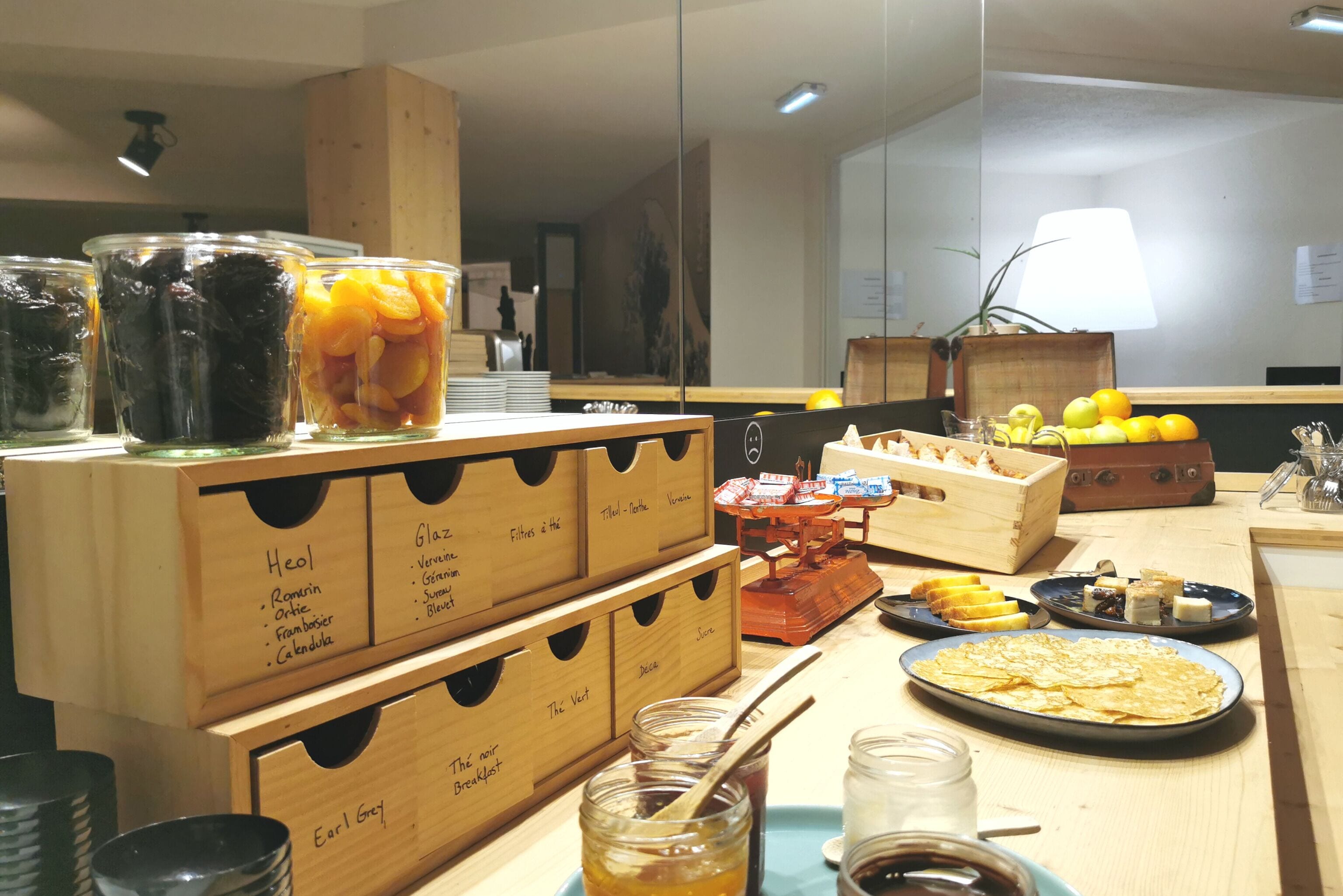 Um buffet de café da manhã com diversos alimentos e recipientes identificados com seus nomes.
