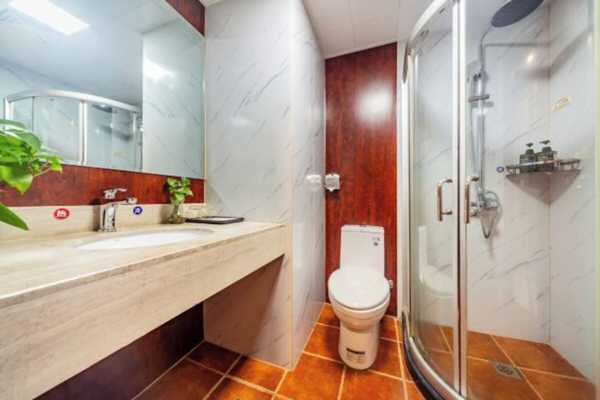 Um banheiro moderno com toucador de mármore, vaso sanitário e chuveiro com divisória de vidro.