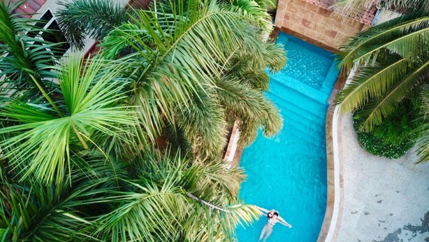 A swimming pool surrounded by lush palm trees. - Melbourne Residence (Siem Reap)