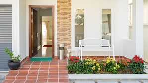 A clean entrance with a bench, potted plants, and a tiled pathway leading to a door. - Melbourne Residence (Siem Reap)