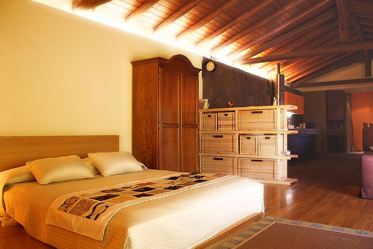 Een slaapkamer met een houten bed, een houten kledingkast en een wandklok.