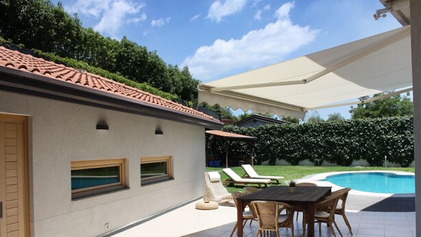 Une terrasse avec une piscine, du mobilier d’extérieur et un espace abrité.