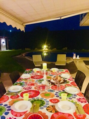 Een buiten eethoek met een tafel voor vier personen, omringd door stoelen, onder een overkapping.