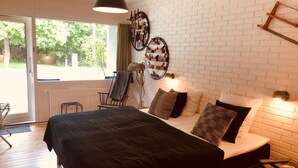 A bedroom with a large bed, a chair, a window, and a brick wall. - Rorvig Centret (Rørvig)