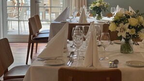 A dining area with tables set for a meal, chairs, and a view of the outdoor seating area. - Rorvig Centret (Rørvig)
