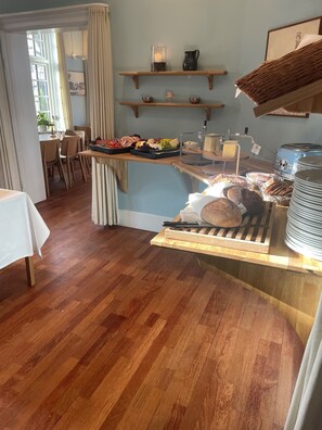 A breakfast buffet area with a variety of food items, a coffee machine, and a seating area with chairs and a table. - Rorvig Centret (Rørvig)