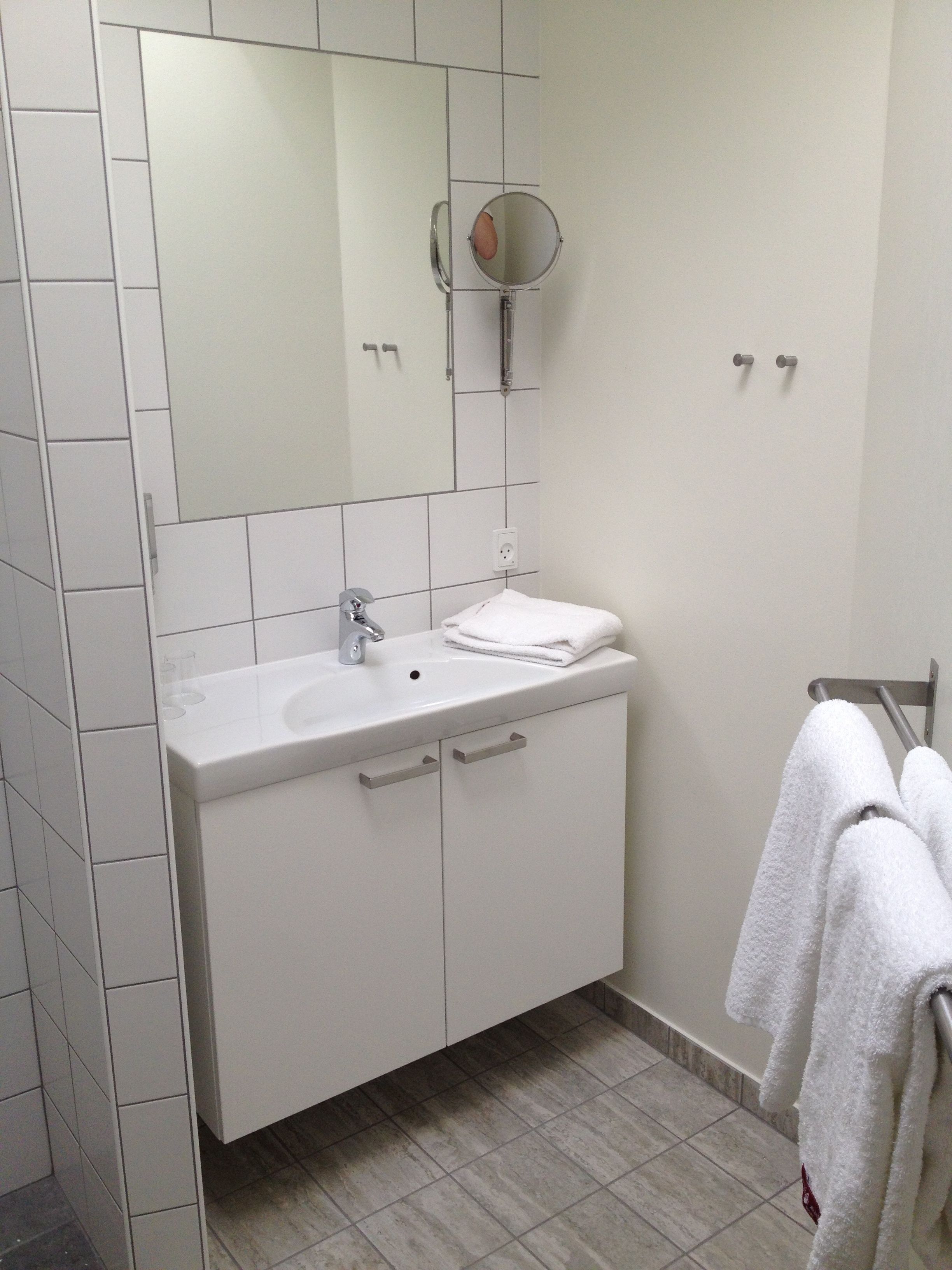 Un baño moderno con un tocador blanco, un espejo y un perchero para toallas.