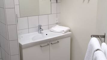 Un baño moderno con un tocador blanco, un espejo y un perchero para toallas.