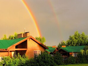 Een gebouw met een groen dak en een zichtbare regenboog op de achtergrond.